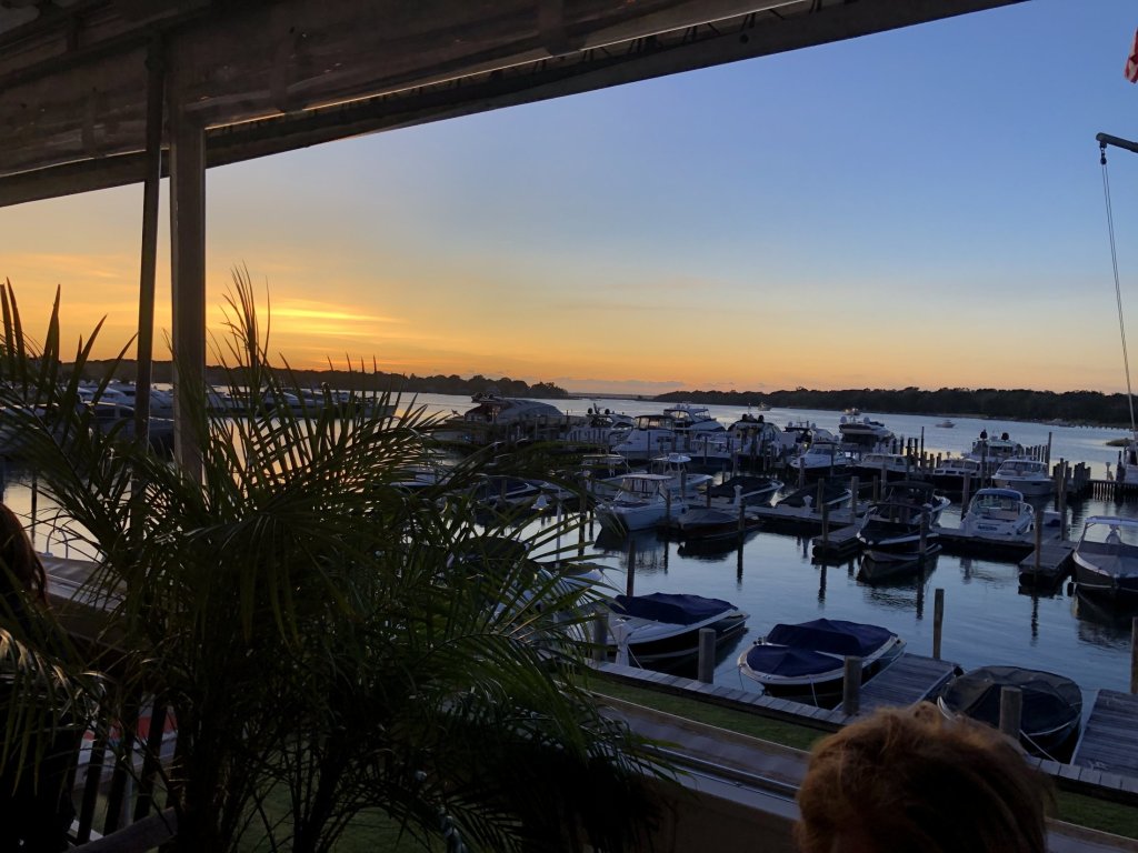 Boats docked in a marina at sunset seen from a waterside porch